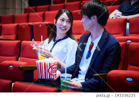 映画館でポップコーンを食べながら映画デートを楽しむカップル 映画館でポップコーンを食べながら映画デートを楽しむカップル 143336235