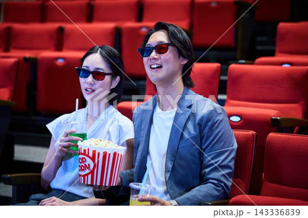 映画館で3Dメガネをかけて映画デートを楽しむカップル 映画館で3Dメガネをかけて映画デートを楽しむカップル 143336839