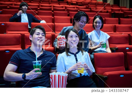 映画館でポップコーンを食べながら映画鑑賞を楽しむ若者たち 映画館でポップコーンを食べながら映画鑑賞を楽しむ若者たち 143338747