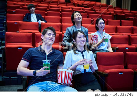 映画館でポップコーンを食べながら映画鑑賞を楽しむ若者たち 143338749