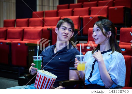 映画館でポップコーンを食べながら映画鑑賞を楽しむ若者たち 映画館でポップコーンを食べながら映画鑑賞を楽しむ若者たち 143338760