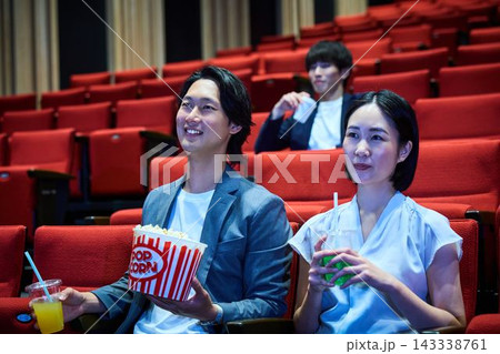 映画館でポップコーンを食べながら映画鑑賞を楽しむ若者たち 映画館でポップコーンを食べながら映画鑑賞を楽しむ若者たち 143338761