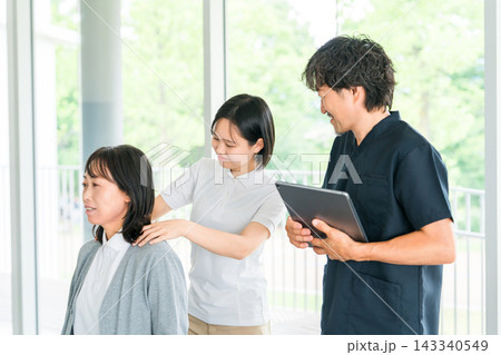 マッサージ,理学療法の研修を受ける若い女性スタッフと教える理学療法士の男性 143340549