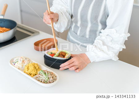 キッチンでお弁当を詰める女性の手元（愛妻弁当） 143341133