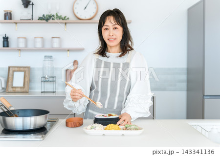 キッチンでお弁当を詰める女性（お母さん,妻,主婦） 143341136