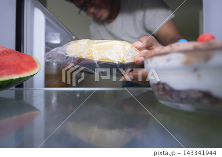 Man takes food out of refrigerator in kitchen during day Man takes food out of refrigerator in kitchen during day 143341944