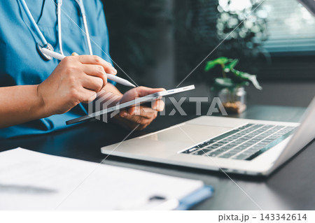 Medical professional using a tablet stylus beside a laptop and stethoscope, illustrating electronic health records, digital documentation, clinical workflow, patient management, Medical professional using a tablet stylus beside a laptop and stethoscope, illustrating electronic health records, digital documentation, clinical workflow, patient management, 143342614