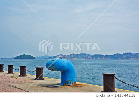 係船柱が置かれた港の岸壁から穏やかな海と遠くの島々を望む風景 係船柱が置かれた港の岸壁から穏やかな海と遠くの島々を望む風景 143344119