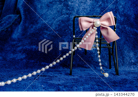 Decorative chair with pink bow and pearl necklace on blue background Decorative chair with pink bow and pearl necklace on blue background 143344270