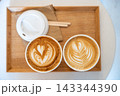 Two Lattes With Latte Art on Wooden Tray in Bright Cafe Setting for Morning Coffee 143344390