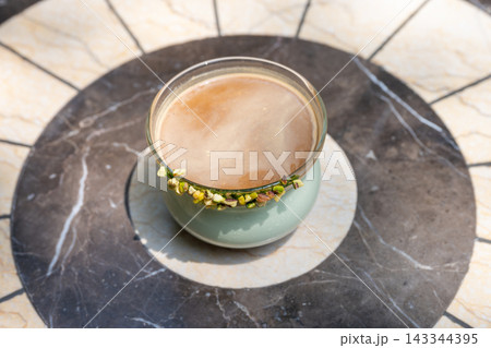 A cup of frothy coffee on a marble table A cup of frothy coffee on a marble table 143344395