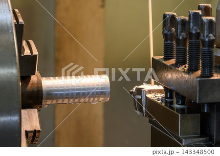 Lathe machine finishing cut on a metal shaft part with liquid coolant in a light blue scene Lathe machine finishing cut on a metal shaft part with liquid coolant in a light blue scene 143348500