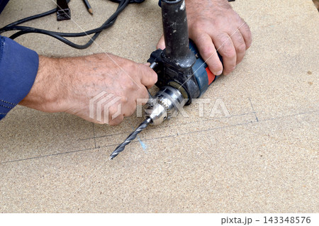 Installing a drill bit into an electric drill. Installing a drill bit into an electric drill. 143348576