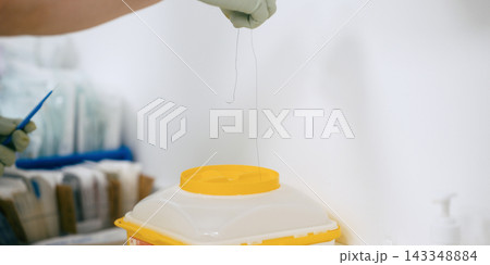 Hand disposing of medical waste into sharps container 143348884