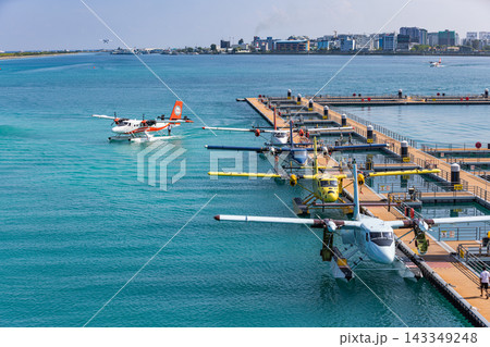 Aerial seaplanes moored floating jetty vivid turquoise Maldives lagoon deep blue tropical arrival hub. Scenic travel wanderlust vista. Exotic journey explore transfer 143349248
