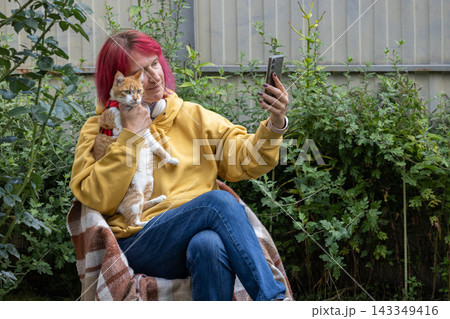 Woman with pink hair taking selfie with cat Woman with pink hair taking selfie with cat 143349416