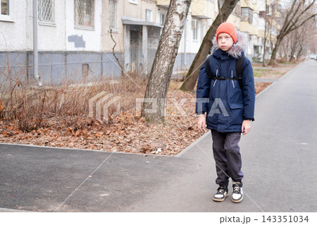 Boy student with backpack leaving apartment building entrance and walking to school, independent child concept Boy student with backpack leaving apartment building entrance and walking to school, independent child concept 143351034