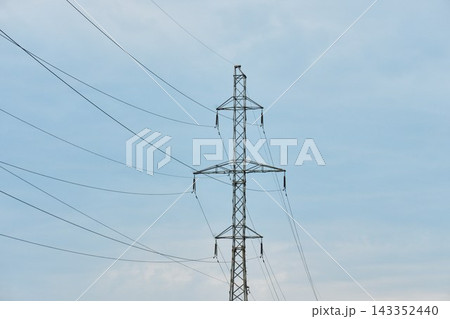Medium shot of a metal transmission pylon with power cables and insulators isolated against a light blue sky Medium shot of a metal transmission pylon with power cables and insulators isolated against a light blue sky 143352440