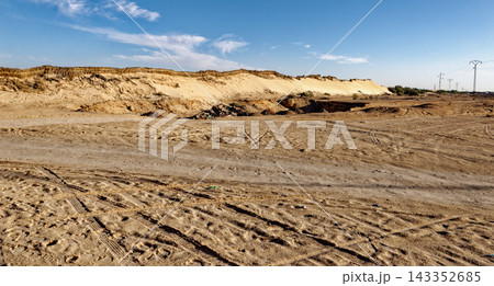 Wide Landscape of Arid Desert Plain with Sandy Ridges and Tire Tracks Under Blue Sky Wide Landscape of Arid Desert Plain with Sandy Ridges and Tire Tracks Under Blue Sky 143352685