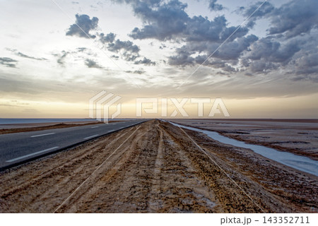 Low Angle Perspective of Empty Straight Highway Stretching Across Flat Salt Desert at Dusk Low Angle Perspective of Empty Straight Highway Stretching Across Flat Salt Desert at Dusk 143352711