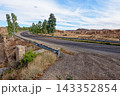 Winding Asphalt Desert Highway with Guardrail and Eucalyptus Trees near Matmata Arid Landscape 143352854