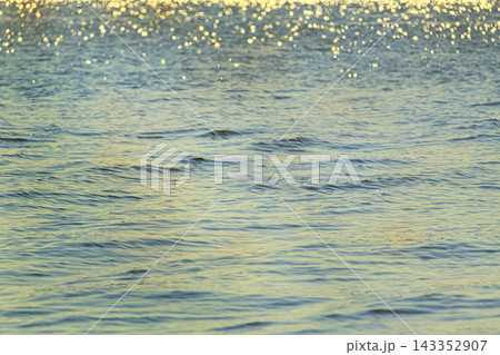 Calm blue water surface with gentle waves and golden sunlight reflections. Calm blue water surface with gentle waves and golden sunlight reflections. 143352907