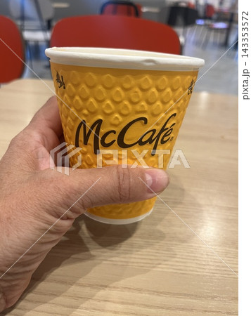 Hand with paper cup of coffee at a fast food restaurant. Hand with paper cup of coffee at a fast food restaurant. 143353572