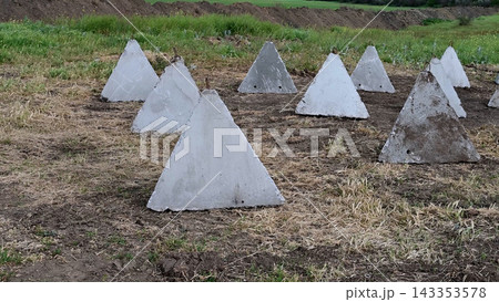 Concrete fortifications dragon's teeth on the field. Concrete fortifications dragon's teeth on the field. 143353578