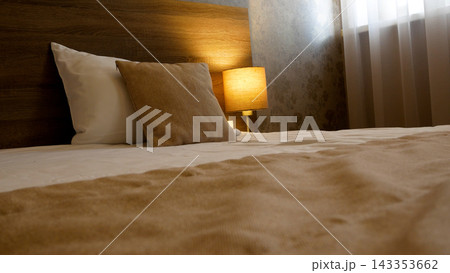 Bedroom interior: Bed with two pillows in pastel colors, next to a table lamp Bedroom interior: Bed with two pillows in pastel colors, next to a table lamp 143353662