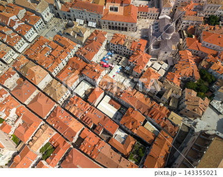 Dubrovnik Croatia rooftops form dense historic center around open stone squares. Overhead view highlights red tile roofs, cathedral architecture, narrow lanes, and bright umbrellas in old town. Dubrovnik Croatia rooftops form dense historic center around open stone squares. Overhead view highlights red tile roofs, cathedral architecture, narrow lanes, and bright umbrellas in old town. 143355021
