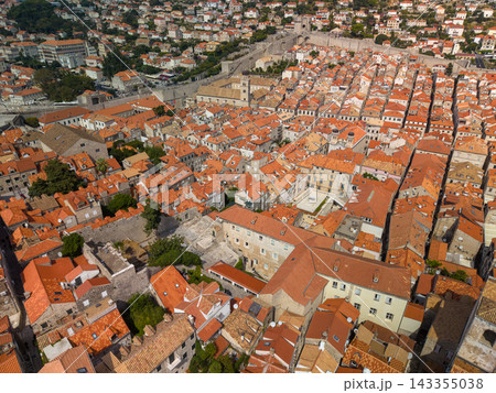 Dubrovnik Croatia spreads beneath elevated viewpoint, showing tightly packed stone houses and red tile roofs within ancient ramparts. Church towers punctuate historic old town architecture. 143355038