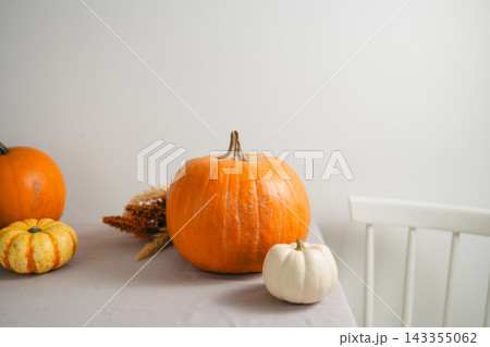 Autumn pumpkin arrangement with orange and white pumpkins on a dining table, minimalist seasonal home decoration with copy space for Halloween, Thanksgiving Autumn pumpkin arrangement with orange and white pumpkins on a dining table, minimalist seasonal home decoration with copy space for Halloween, Thanksgiving 143355062