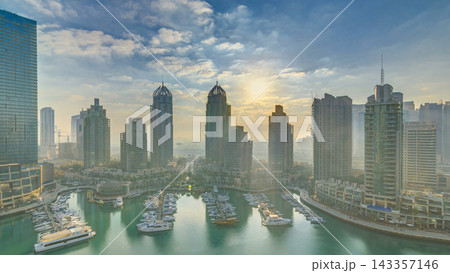View of modern skyscrapers shining in sunrise lights timelapse in Dubai Marina in Dubai, UAE. View of modern skyscrapers shining in sunrise lights timelapse in Dubai Marina in Dubai, UAE. 143357146