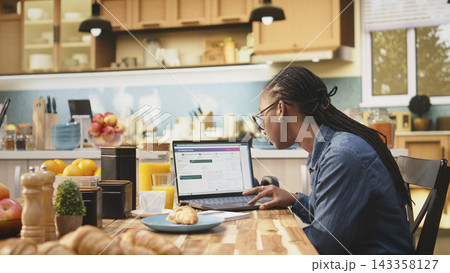 African american client checking dispatch via tracking number on software, ensuring real time delivery and courier service. Woman monitoring delivery status without delay, everyday life. African american client checking dispatch via tracking number on software, ensuring real time delivery and courier service. Woman monitoring delivery status without delay, everyday life. 143358127