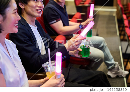 劇場でペンライトとドリンクを持ちライブ鑑賞を楽しむ観客 143358820