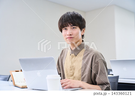 パソコンを開いて学習に取り組む20代の男性 パソコンを開いて学習に取り組む20代の男性 143360121