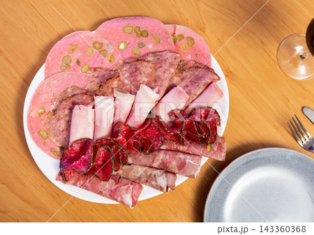 Slices of butifarra and smoked sausage dished up in a service plate on laid restaurant table Slices of butifarra and smoked sausage dished up in a service plate on laid restaurant table 143360368