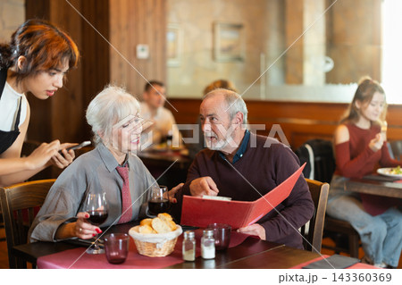 Young female waitress takes order from elderly couple 143360369
