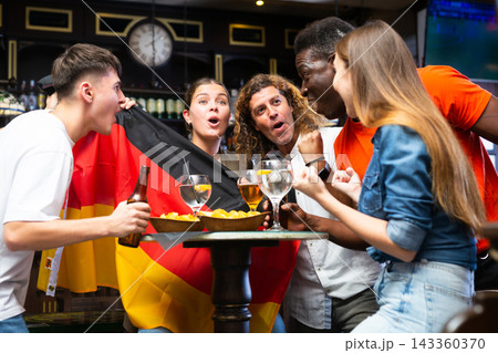 Excited sports fans celebrating victory of favorite German team in bar Excited sports fans celebrating victory of favorite German team in bar 143360370
