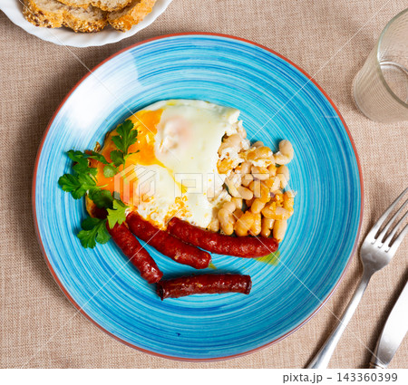 Delicious chistorra sausages with scrambled eggs and beans Delicious chistorra sausages with scrambled eggs and beans 143360399