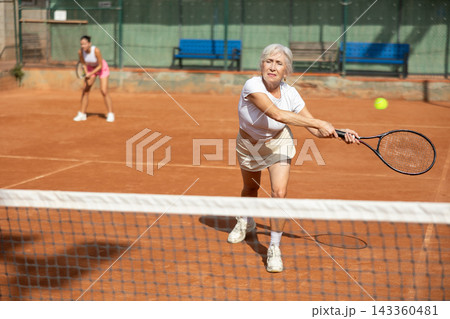 Young woman playing tennis with older woman 143360481
