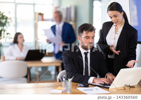 Woman head of a bank office stands with a male employee and helps with work issues 143360560