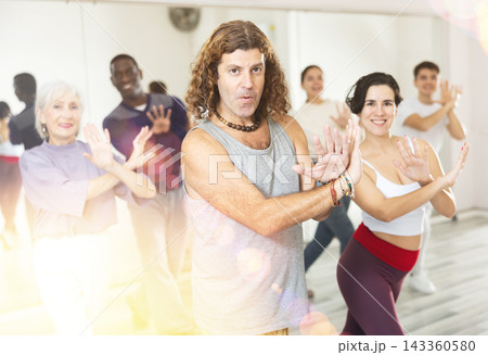 Caucasian guy practising dance moves with other people in dance studio Caucasian guy practising dance moves with other people in dance studio 143360580