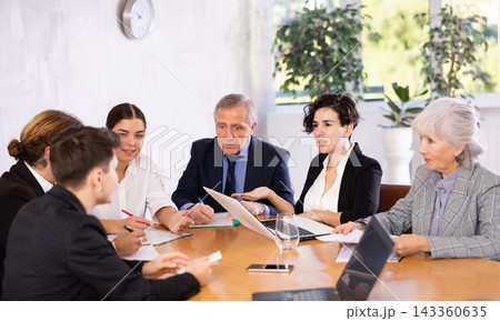 Concentrated young adult old office workers discussing ideas while gathering at table in meeting room 143360635