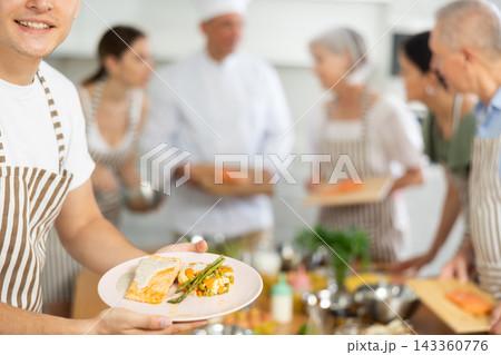 Plate of finished dish in hands of participant of cooking course 143360776