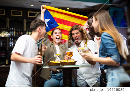 Emotional diverse sport fans with flag of Estelada, rejoicing with of beer in the pub 143360864