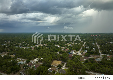 Dark stormy clouds forming on gloomy sky before heavy rainfall over suburban town area 143361375