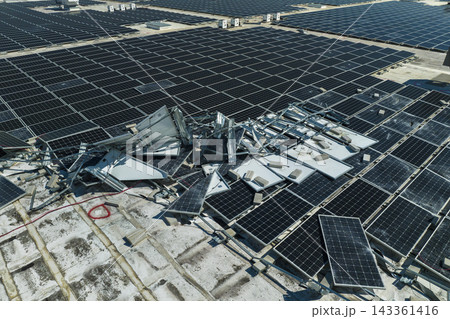 Consequences of natural disaster. Damaged by hurricane wind photovoltaic solar panels mounted on industrial building roof for producing green ecological electricity Consequences of natural disaster. Damaged by hurricane wind photovoltaic solar panels mounted on industrial building roof for producing green ecological electricity 143361416