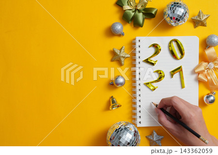 Hand writing in spiral notebook for New Year planning on yellow background 143362059
