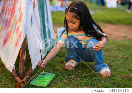 preschool child girl painting watercolors on canvas outdoors in park 143364110